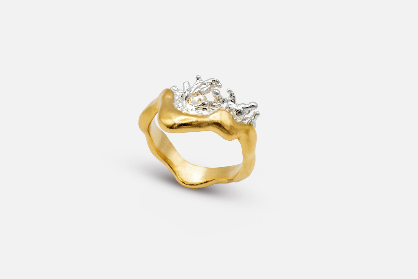 A gold vermeil and silver ring with a wavy, organic shape and a splash of water crafted in silver in the center.