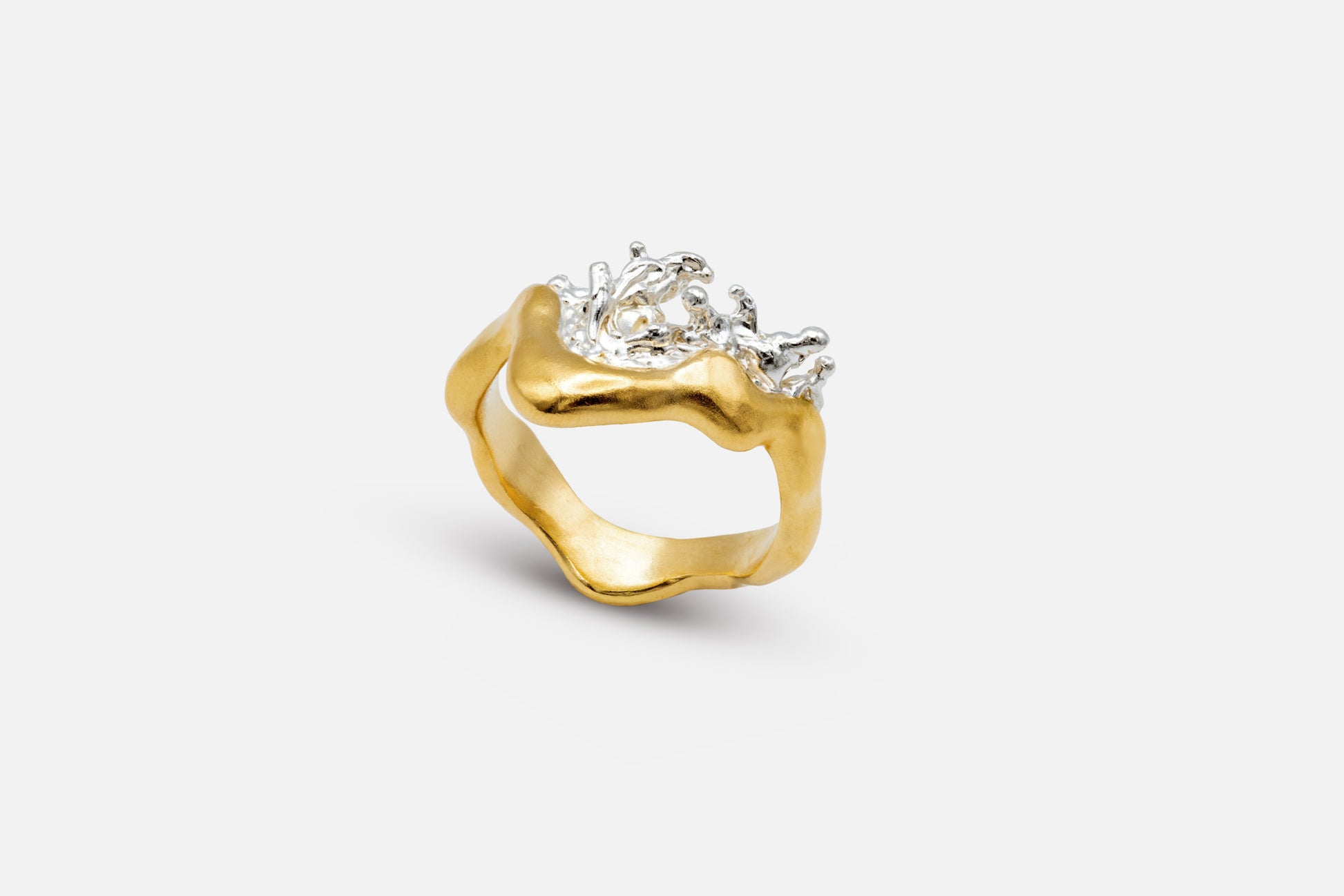 A gold vermeil and silver ring with a wavy, organic shape and a splash of water crafted in silver in the center.