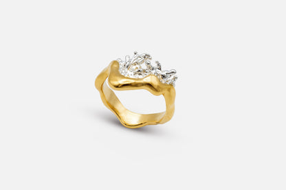 A gold vermeil and silver ring with a wavy, organic shape and a splash of water crafted in silver in the center.