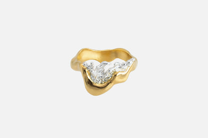A gold vermeil and silver ring with a wavy, organic shape and a splash of water crafted in silver in the center.