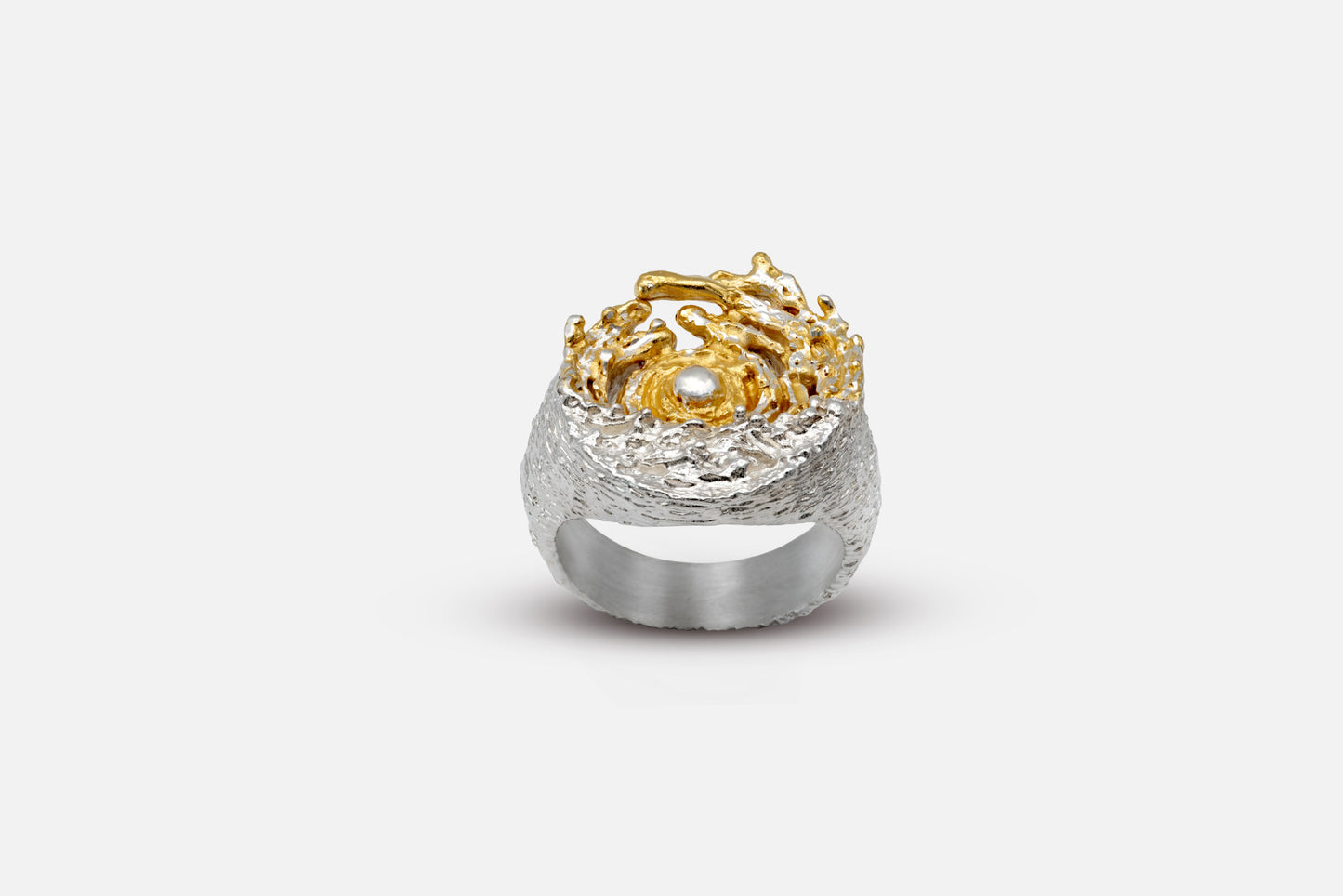 A unique textured silver and gold vermeil ring featuring a gold swirl with a central sun, set against a textured silver background like the sea and tides moving at dawn, on a clean white background.