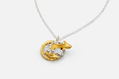 A gold vermeil and silver pendant necklace featuring two fish leaping out of water on a delicate silver chain, shown against a light gray background.