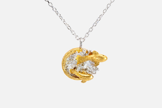 A gold vermeil and silver pendant necklace featuring two fish leaping out of water on a delicate silver chain, shown against a light gray background.