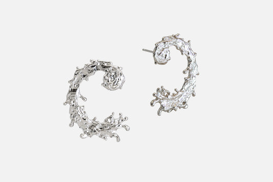A pair of silver earrings with a textured, organic design like the waters of the sea swirling in a circular pattern, displayed on a clean light gray background.