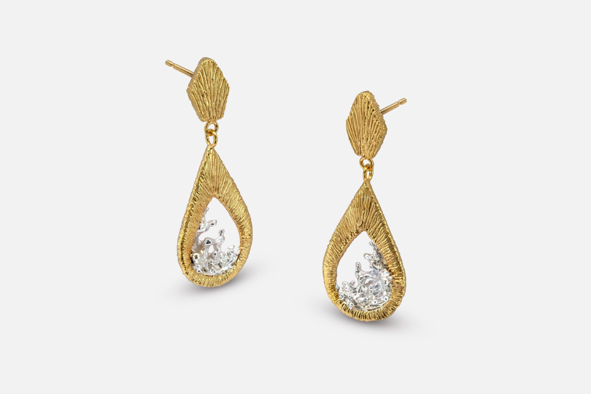 A pair of gold vermeil and silver teardrop dangle earrings with a textured, ribbed gold top and a water shaped silver center, shown against a light gray background.