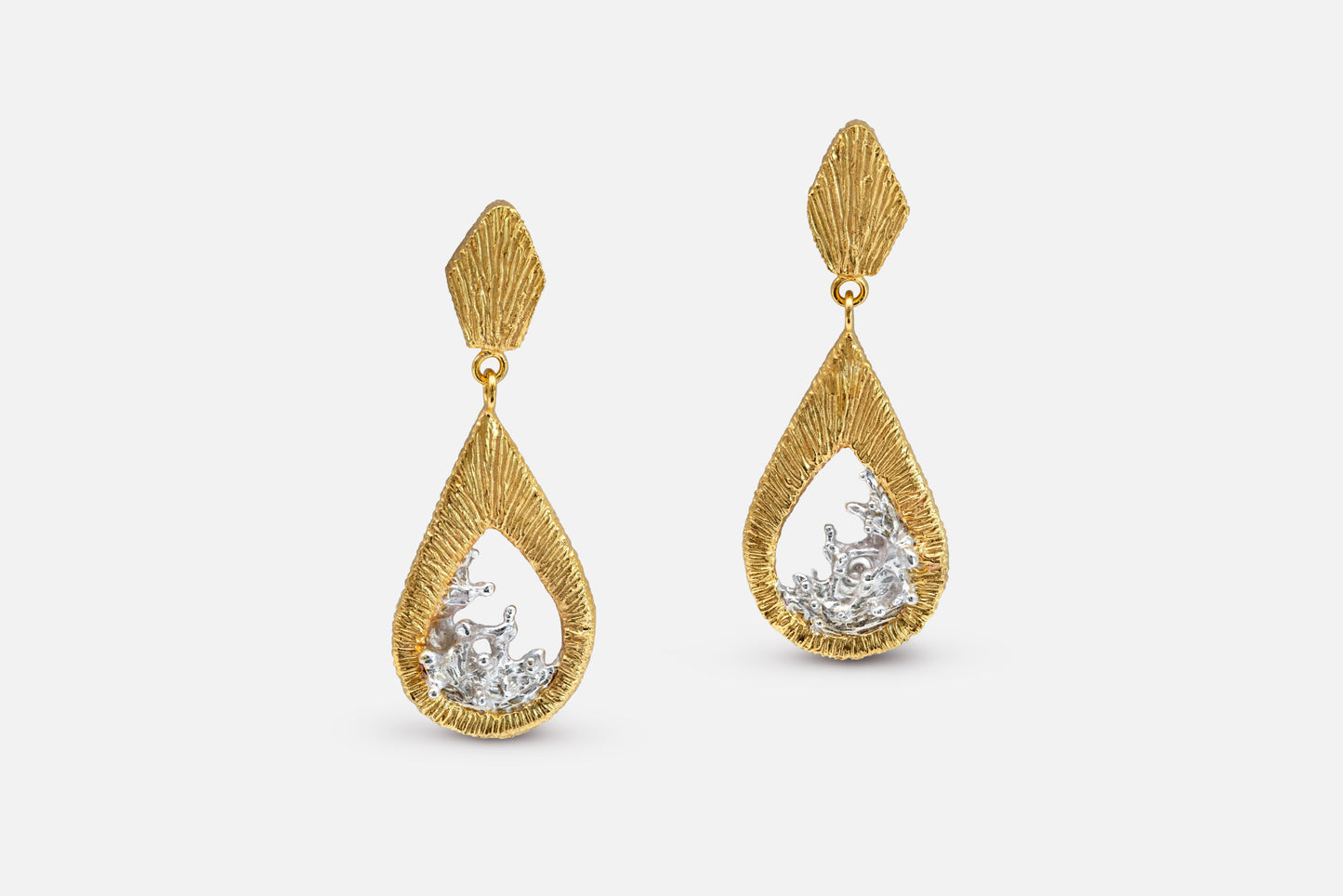 A pair of gold vermeil and silver teardrop dangle earrings with a textured, ribbed gold top and a water shaped silver center, shown against a light gray background.