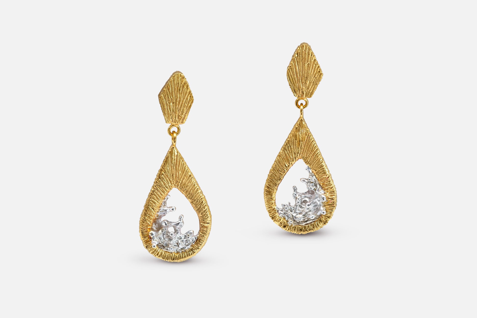 A pair of gold vermeil and silver teardrop dangle earrings with a textured, ribbed gold top and a water shaped silver center, shown against a light gray background.