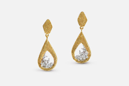 A pair of gold vermeil and silver teardrop dangle earrings with a textured, ribbed gold top and a water shaped silver center, shown against a light gray background.